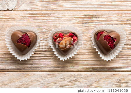 chocolate sweets in the form of a heart with fruits and nuts on a colored background. top view with space for text, holiday concept 111041066