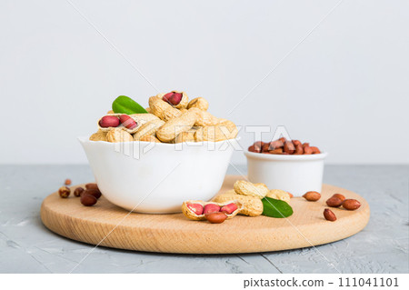 Fresh healthy peanuts in bowl on colored table background. Top view Healthy eating bertholletia concept. Super foods Fresh healthy peanuts in bowl on colored table background. Top view Healthy eating bertholletia concept. Super foods 111041101