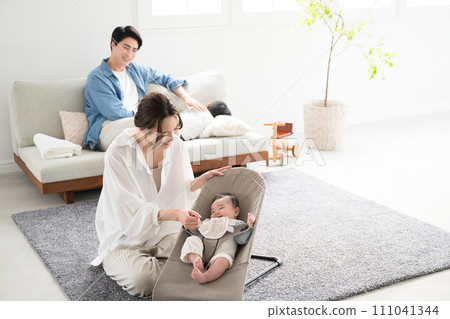 An Asian (Japanese) family of four raising children in the living room. Baby and mother looking at each other. 111041344