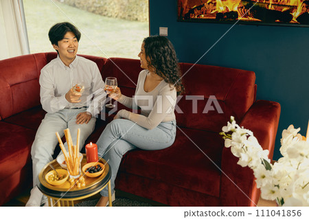 Smiling friends enjoying in conversation and drinking wine during holiday party at home 111041856