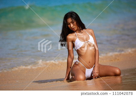 Beautiful asian girl in white bikini posing at the tropical beach 111042078