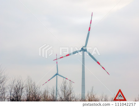 Wind turbine station windmill park next to the road in Austria in cloudy weather. Wind turbine station windmill park next to the road in Austria in cloudy weather. 111042257