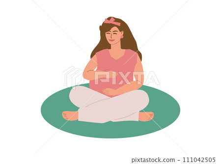 A young pregnant woman sits cross-legged on a mat A young pregnant woman sits cross-legged on a mat 111042505
