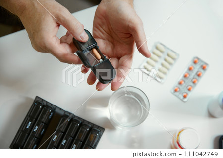 Hands of a senior man holding pill box, medication containers labeled with days of week. Organizer for daily pills and vitamins Hands of a senior man holding pill box, medication containers labeled with days of week. Organizer for daily pills and vitamins 111042749