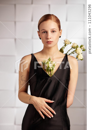 Beautiful young with special needs woman with flowers in her hand holding a flower, woman in black dress. Diversity handicap and flowers. Beautiful young with special needs woman with flowers in her hand holding a flower, woman in black dress. Diversity handicap and flowers. 111043296