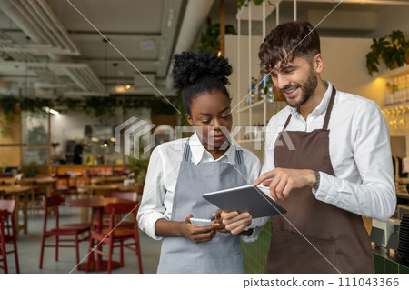 Pizzeria worker standing together and discussing something Pizzeria worker standing together and discussing something 111043366