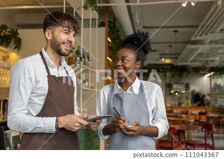Pizzeria worker standing together and discussing something Pizzeria worker standing together and discussing something 111043367