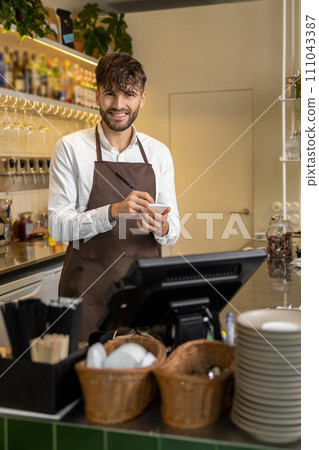 Waiter in pizzeria making notes and smiling Waiter in pizzeria making notes and smiling 111043387