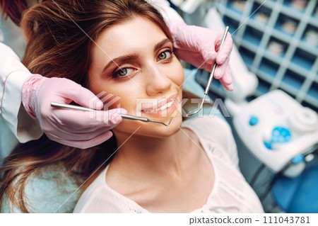 Young woman at the dentist's chair during a dental procedure. Overview of dental caries prevention. Young woman at the dentist's chair during a dental procedure. Overview of dental caries prevention. 111043781