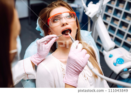Young woman at the dentist's chair during a dental procedure. Overview of dental caries prevention. 111043849