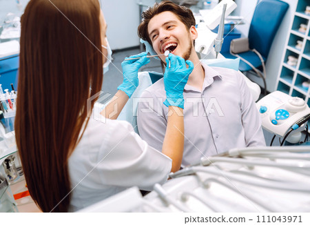 Young man at the dentist's chair during a dental procedure. Overview of dental caries prevention. Young man at the dentist's chair during a dental procedure. Overview of dental caries prevention. 111043971