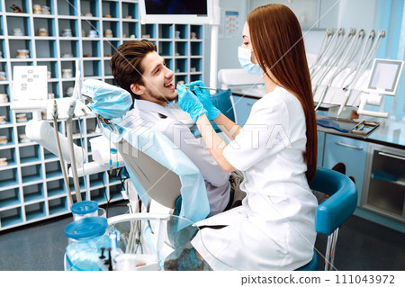 Young man at the dentist's chair during a dental procedure. Overview of dental caries prevention. Young man at the dentist's chair during a dental procedure. Overview of dental caries prevention. 111043972