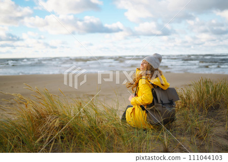 Pretty female traveler walks on shore near tranquil sea at sunser. Nature paradise Pretty female traveler walks on shore near tranquil sea at sunser. Nature paradise 111044103