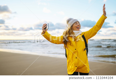 Woman travel blogger takes selfie for social networks by sea sunset. Travel, tourism, relax concept 111044104
