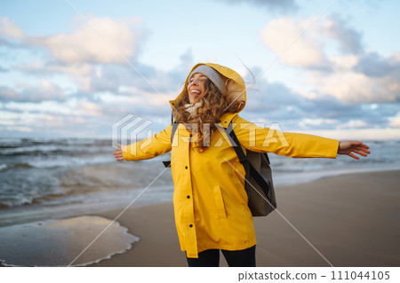 Pretty female traveler walks on shore near tranquil sea at sunser. Nature paradise Pretty female traveler walks on shore near tranquil sea at sunser. Nature paradise 111044105