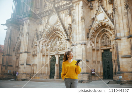 woman in Prague having walking tour, using phone and walking woman in Prague having walking tour, using phone and walking 111044397