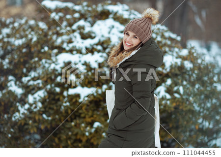 smiling modern woman outdoors in city park in winter 111044455