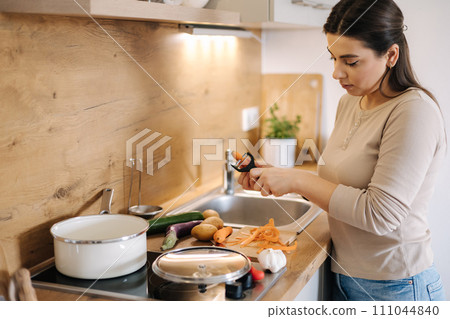 A young beautiful woman is preparing lunch in her kitchen at home. Vegan A young beautiful woman is preparing lunch in her kitchen at home. Vegan 111044840