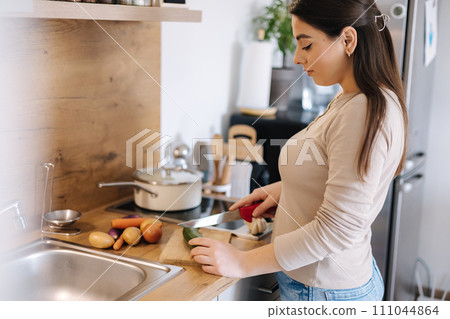 A young beautiful woman is preparing lunch in her kitchen at home. Vegan A young beautiful woman is preparing lunch in her kitchen at home. Vegan 111044864