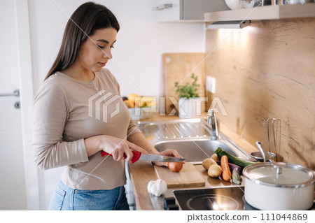 A young beautiful woman is preparing lunch in her kitchen at home. Vegan A young beautiful woman is preparing lunch in her kitchen at home. Vegan 111044869
