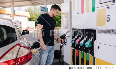 Handsome young man refueling car at gas station. Petrol concept. Side view Handsome young man refueling car at gas station. Petrol concept. Side view 111045082