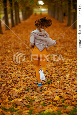 Seen from behind woman in fitness clothes in park jogging 111045150
