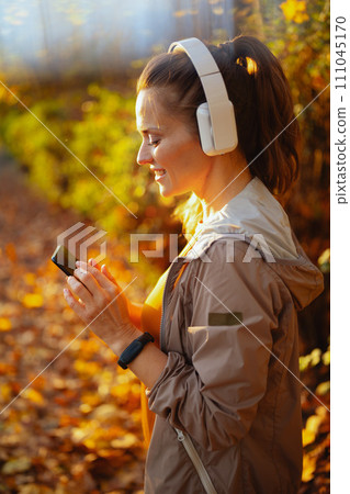 elegant woman in fitness clothes in park with headphones 111045170