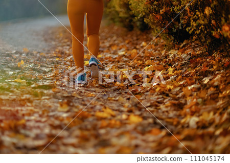 Closeup on female in fitness clothes in park running 111045174