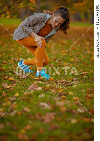 sad modern woman in fitness clothes in park got leg injury sad modern woman in fitness clothes in park got leg injury 111045180