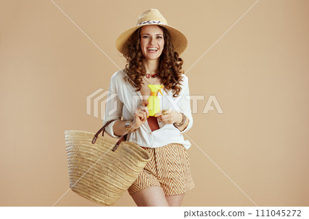 smiling elegant housewife in blouse and shorts on beige 111045272