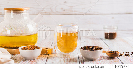 Fresh buckwheat tea in a glass, teapot and granules in a bowl on the table web banner Fresh buckwheat tea in a glass, teapot and granules in a bowl on the table web banner 111045781