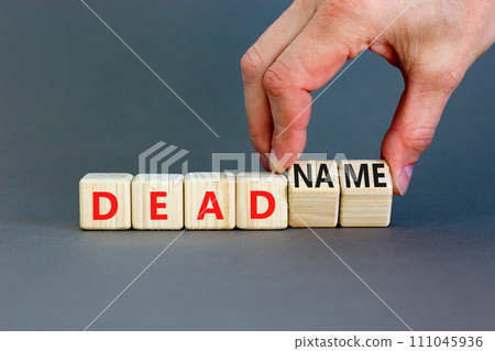 Deadname or name symbol. Concept words Deadname or Name on beautiful wooden blocks. Beautiful grey table grey background. Transgender hand. Business, deadname or name concept. Copy space. 111045936