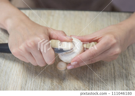 The process of peeling mushrooms. A woman's hands peel mushrooms with a knife, close-up. Cooking mushrooms. The process of peeling mushrooms. A woman's hands peel mushrooms with a knife, close-up. Cooking mushrooms. 111046180