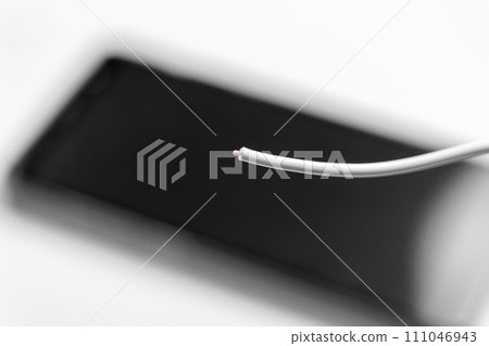Damaged torn white charger cable with smartphone close up 111046943