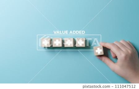 Value add concept. Hand place wooden cube with plus sign on light blue background. Positive thinking or personal growth and development. download style which means value added. value add for business. Value add concept. Hand place wooden cube with plus sign on light blue background. Positive thinking or personal growth and development. download style which means value added. value add for business. 111047512