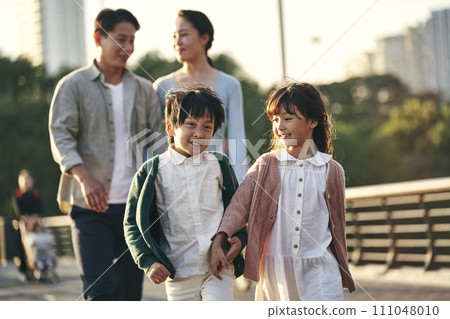asian family with two children taking a walk in city park asian family with two children taking a walk in city park 111048010