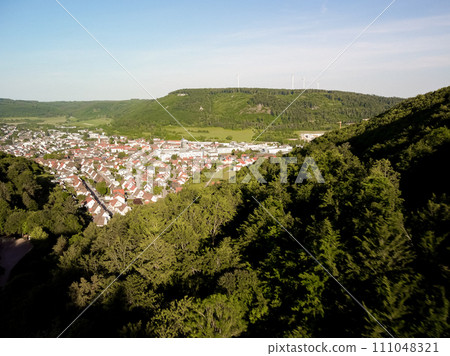 A scenic view of a town nestled between lush green hills under a clear sky 111048321
