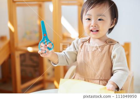 1-year-old child making crafts, first scissors training 111049950
