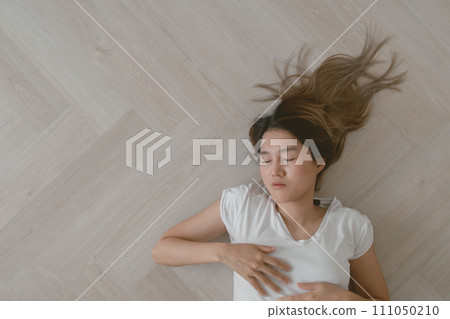 Asian woman wears white t-shirt lie on the wooden floor exhaustedly. Asian woman wears white t-shirt lie on the wooden floor exhaustedly. 111050210