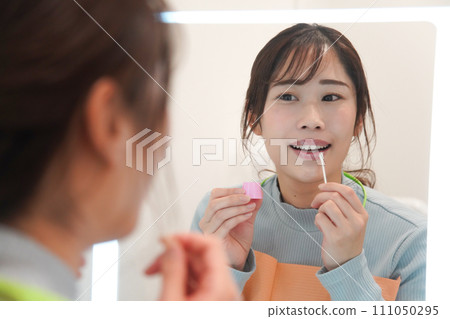 一位女士在嘴唇上塗抹凡士林 一位女士在嘴唇上塗抹凡士林 111050295