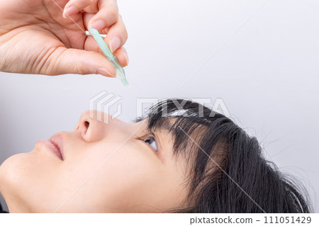 Woman applying eye drops Woman applying eye drops 111051429