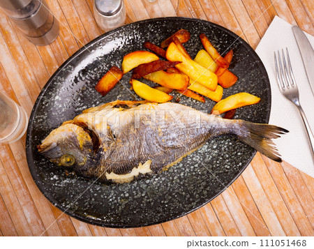 Baked dorada fish with vegetable garnish of fried potatoes 111051468