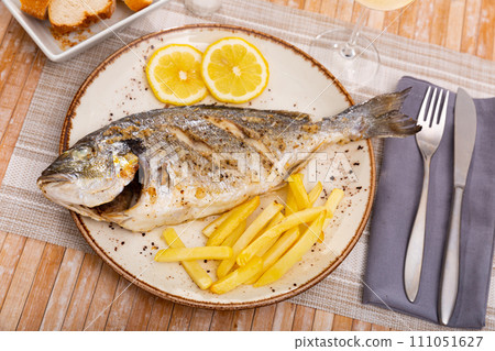 Baked dorada with french fries and fresh lemon slice 111051627