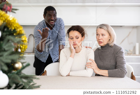 Elderly woman calms down woman during quarrel with man 111052292