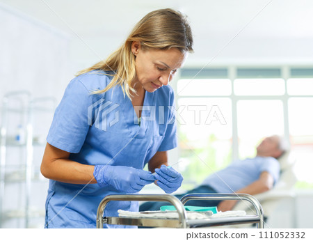 Concentrated woman doctor checking instruments for medical procedures Concentrated woman doctor checking instruments for medical procedures 111052332