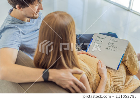 Expectant couple joyfully selects a name for their unborn son, savoring the special moment of choosing a meaningful identity for their growing family 111052783