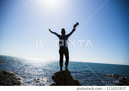 Woman photographer enjoy the view on sunrise seaside rocks Woman photographer enjoy the view on sunrise seaside rocks 111052837