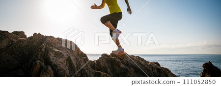 Woman runner legs running on sunrise seaside rocks 111052850