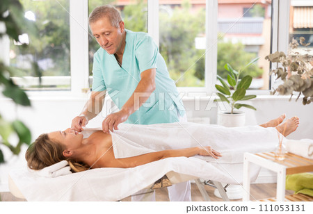 female patient under towel on massage table 111053131