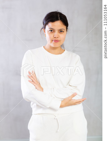 Confident young woman standing with crossed arms on gray background 111053164
